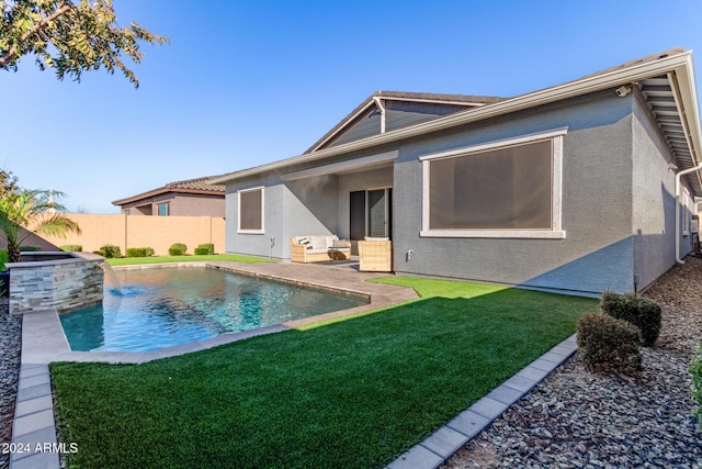 back of property with a fenced in pool and a lawn