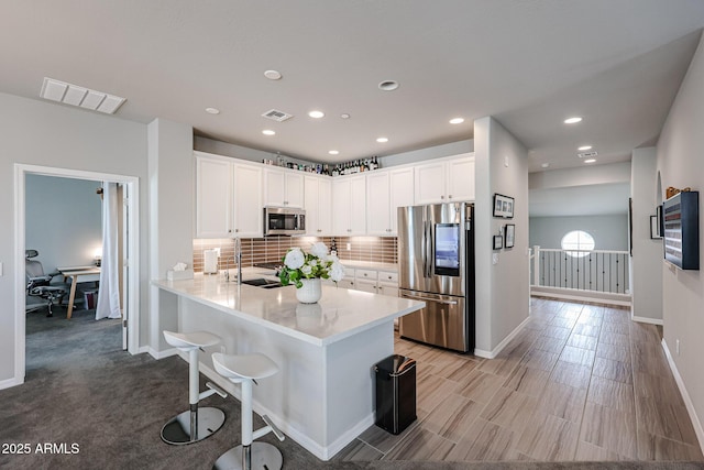 kitchen with white cabinetry, appliances with stainless steel finishes, decorative backsplash, and kitchen peninsula