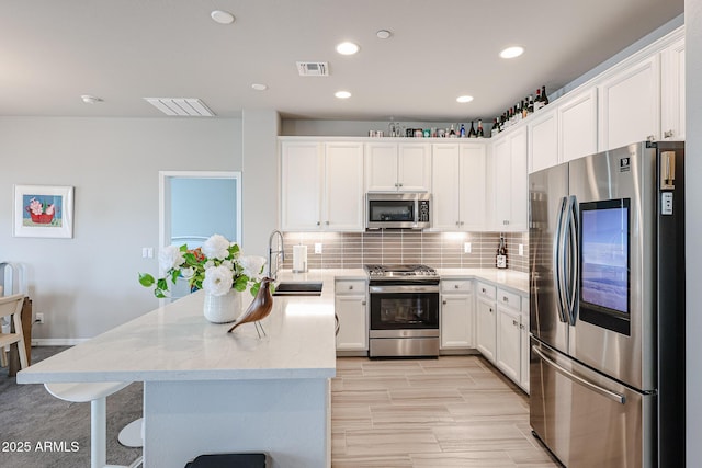 kitchen featuring appliances with stainless steel finishes, tasteful backsplash, white cabinetry, sink, and light stone countertops