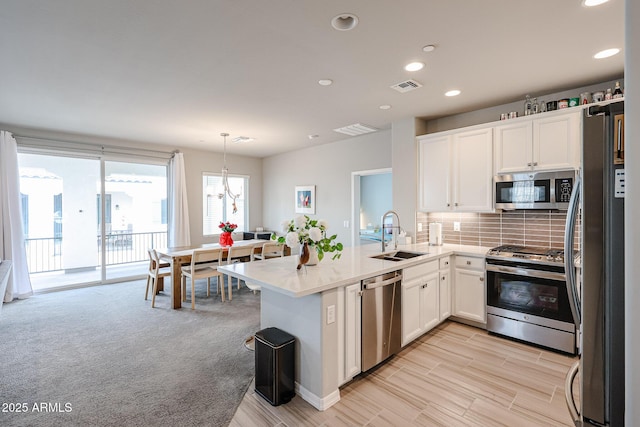 kitchen featuring sink, hanging light fixtures, backsplash, appliances with stainless steel finishes, and white cabinets