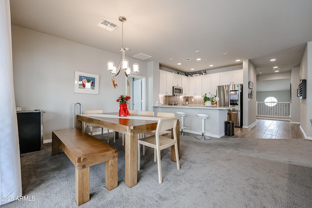 carpeted dining room featuring sink and a notable chandelier