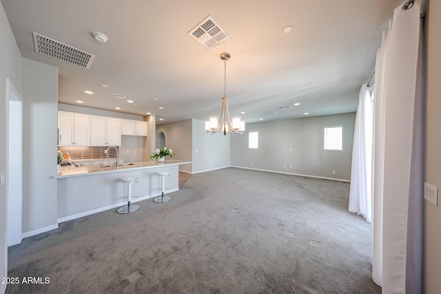 kitchen featuring visible vents, carpet floors, a chandelier, and white cabinetry