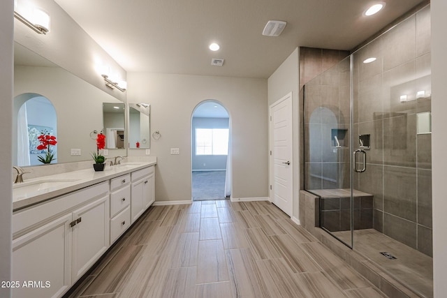 full bath with double vanity, a sink, visible vents, and a stall shower