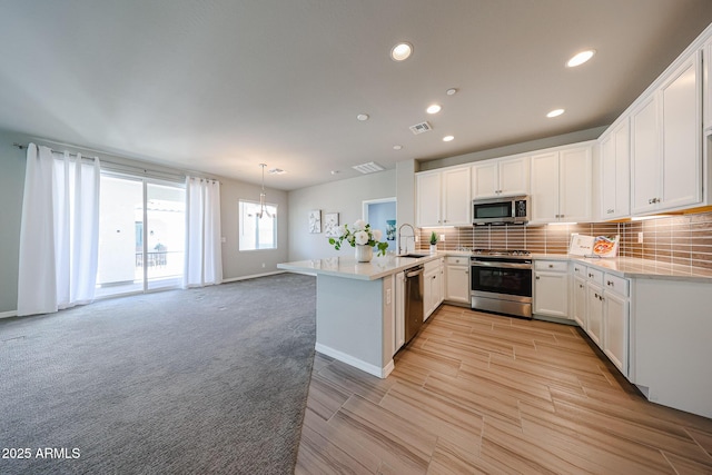 kitchen with light countertops, a peninsula, appliances with stainless steel finishes, visible vents, and recessed lighting