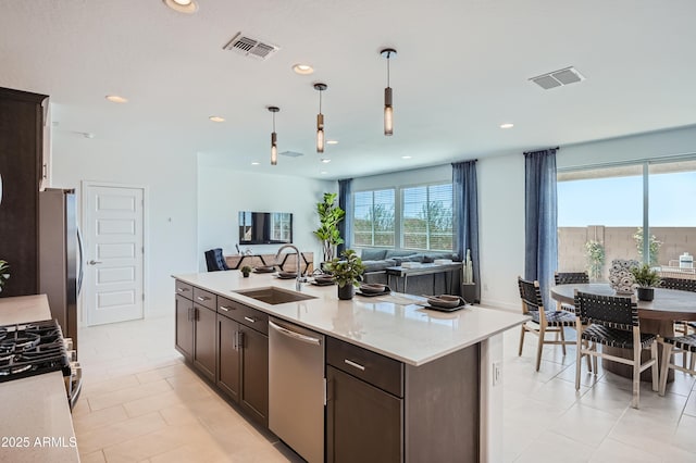 10136 E Ursula Ave, Mesa, AZ 85212 - kitchen with appliances with stainless steel finishes, dark brown cabinets, open floor plan, hanging light fixtures, and a kitchen island with sink