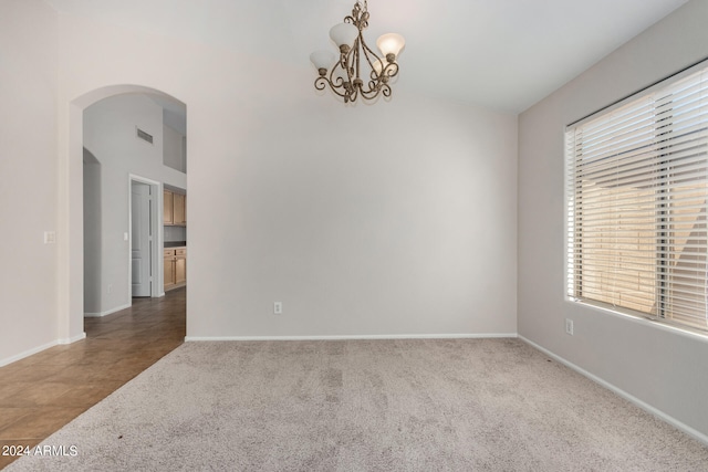 empty room featuring plenty of natural light, a notable chandelier, and carpet floors