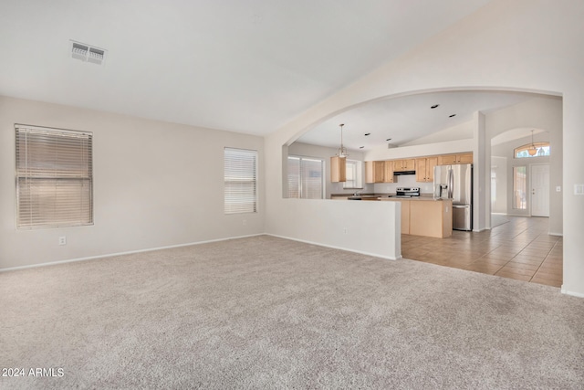 unfurnished living room with light carpet, lofted ceiling, and a healthy amount of sunlight