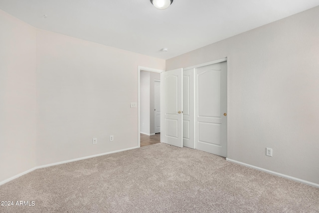 unfurnished bedroom with light colored carpet and a closet