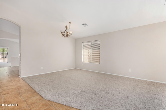 carpeted spare room featuring an inviting chandelier