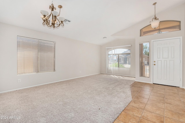 carpeted foyer entrance featuring a chandelier and vaulted ceiling