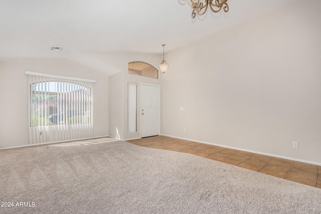 tiled empty room featuring lofted ceiling and an inviting chandelier