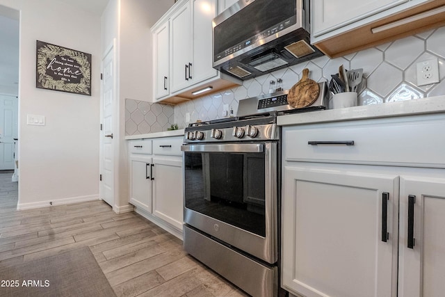 kitchen with light countertops, backsplash, white cabinets, light wood-style floors, and stainless steel appliances
