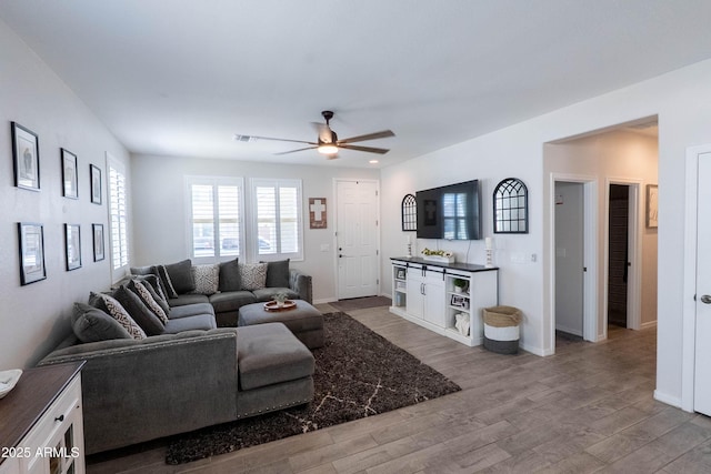 living room with baseboards, wood finished floors, and ceiling fan