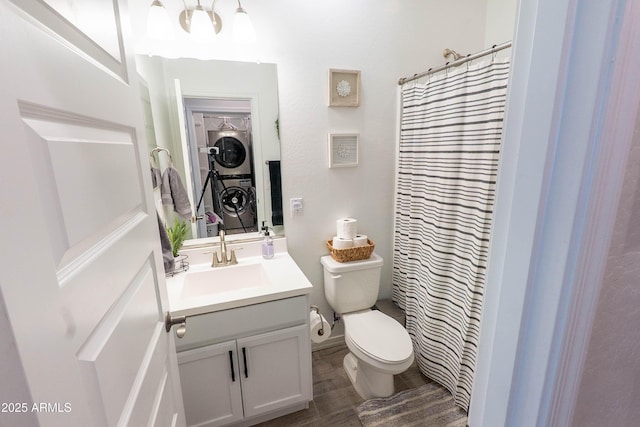 full bath with vanity, curtained shower, stacked washer and clothes dryer, toilet, and wood finished floors