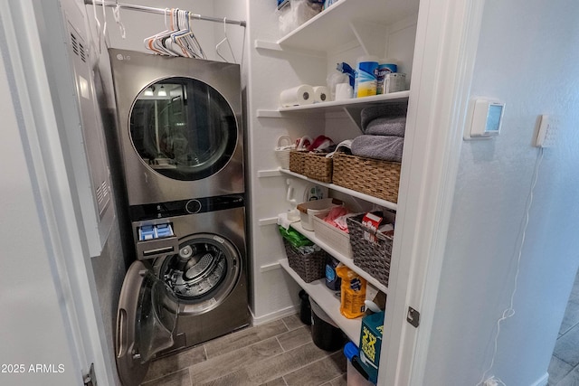 laundry room with stacked washer / dryer, laundry area, baseboards, and wood tiled floor