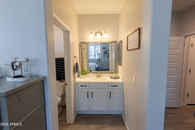 ensuite bathroom featuring toilet, connected bathroom, vanity, and wood finished floors