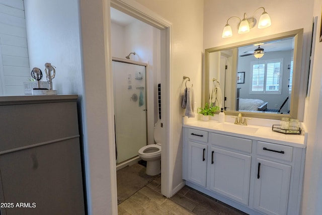 ensuite bathroom with vanity, ensuite bathroom, toilet, a shower stall, and ceiling fan