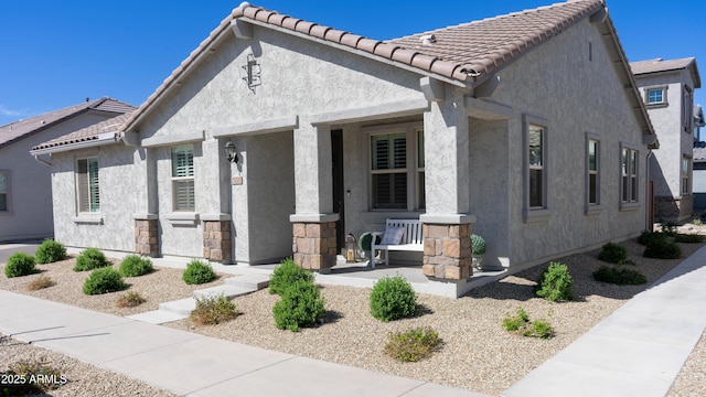 view of front of property featuring a porch, stucco siding, and a tile roof