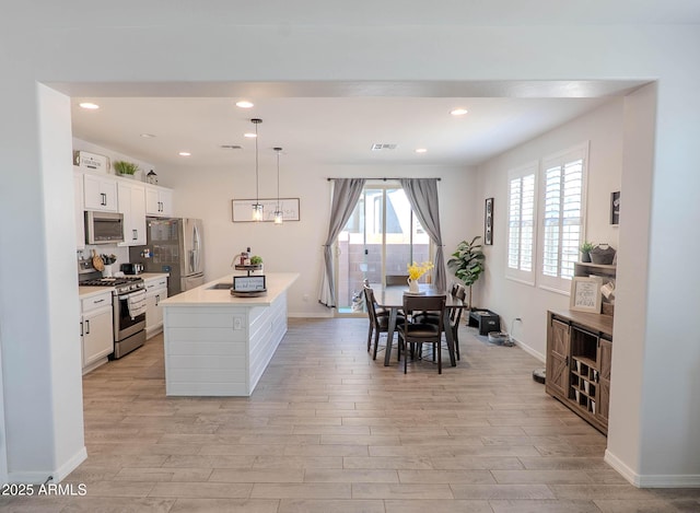 kitchen with baseboards, light wood-style flooring, light countertops, white cabinetry, and appliances with stainless steel finishes