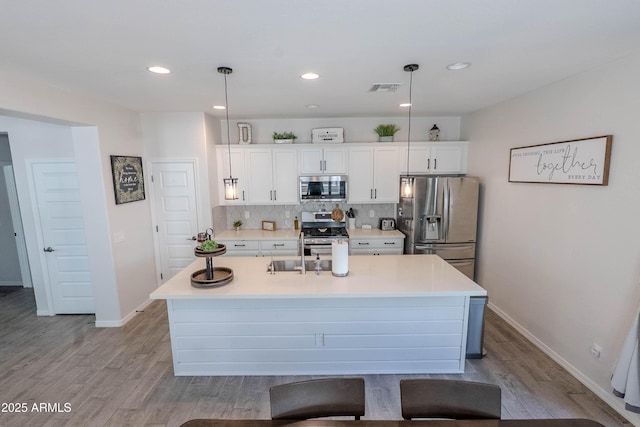 kitchen with white cabinets, light wood-style floors, appliances with stainless steel finishes, and visible vents