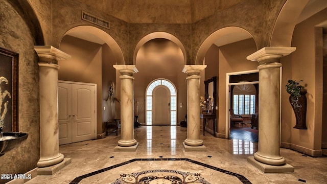 foyer entrance with a towering ceiling and decorative columns