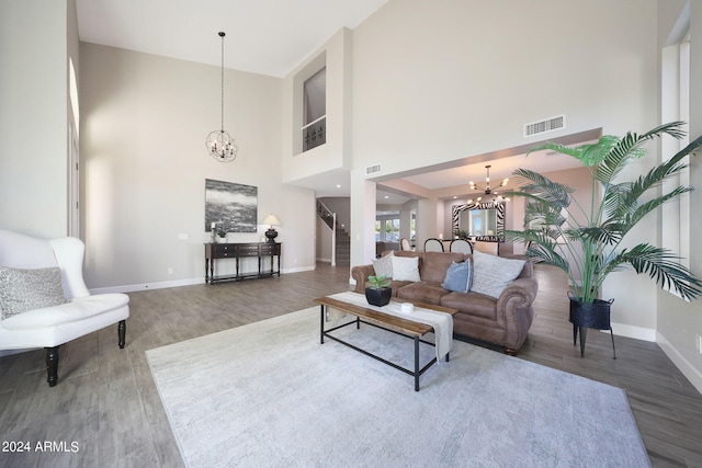 living room featuring wood-type flooring, a notable chandelier, and a towering ceiling