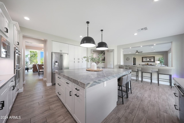 kitchen with appliances with stainless steel finishes, white cabinetry, and a kitchen island