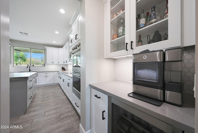 kitchen with tasteful backsplash, light hardwood / wood-style flooring, and white cabinets