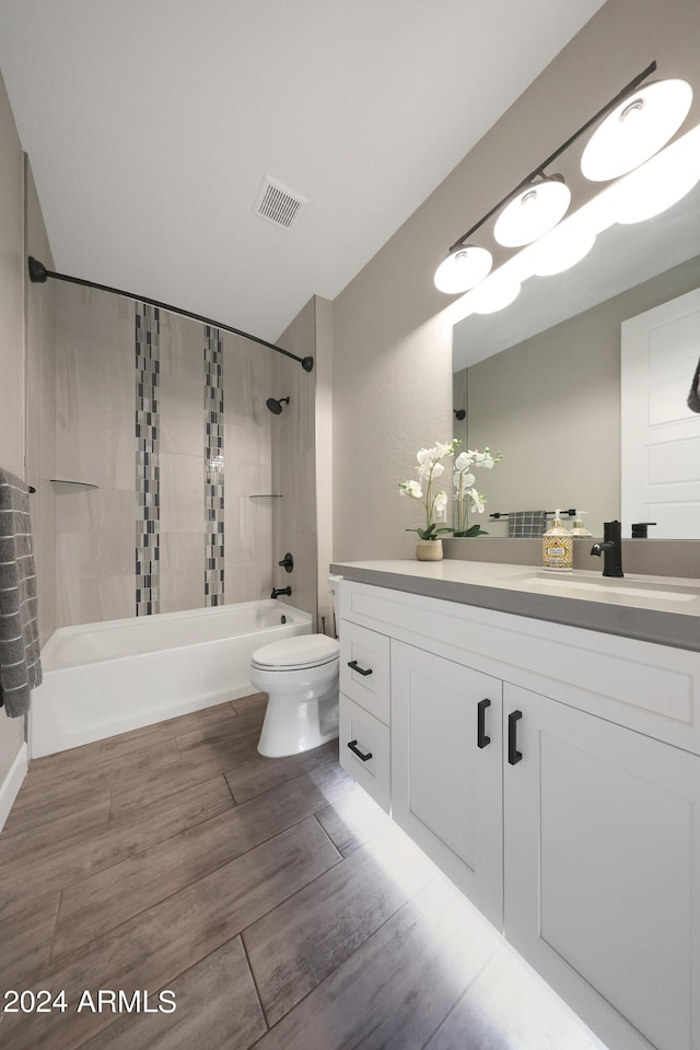 full bathroom with hardwood / wood-style floors, vanity, toilet, and tiled shower / bath