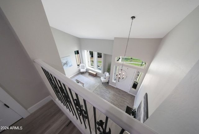 staircase featuring a notable chandelier, high vaulted ceiling, and hardwood / wood-style flooring