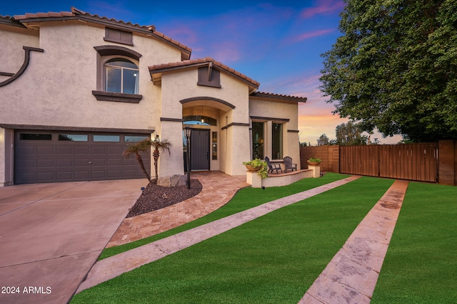 mediterranean / spanish-style home featuring a garage and a yard