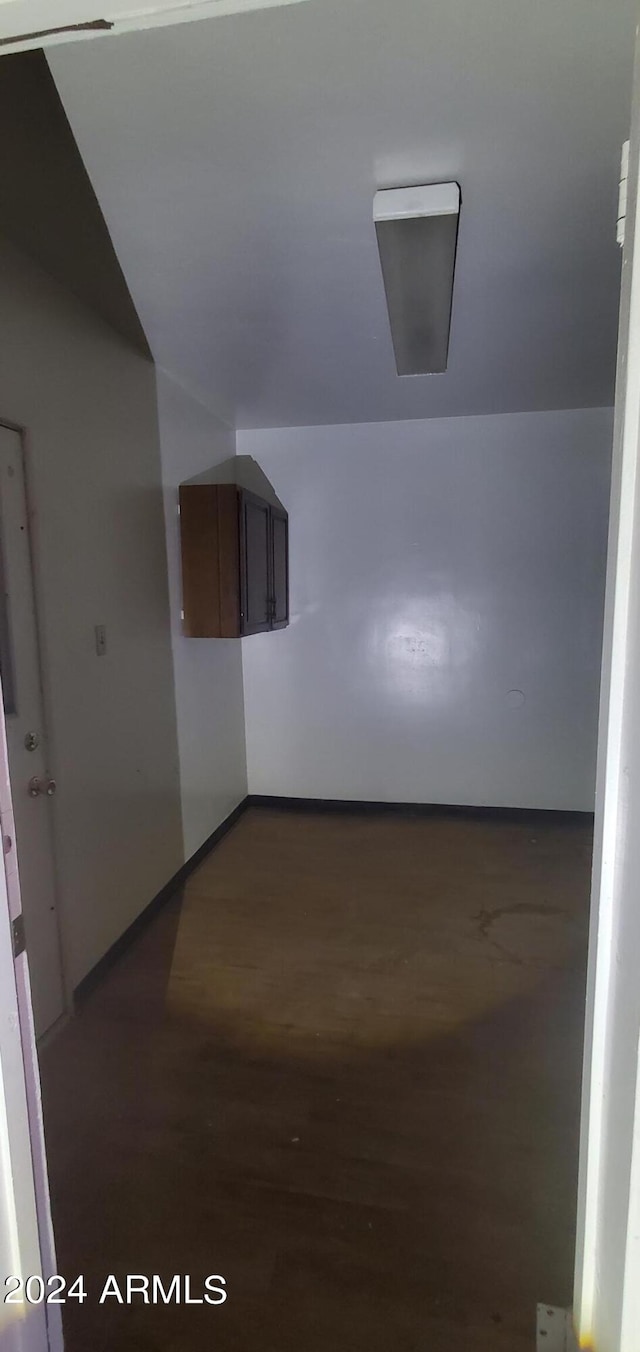 corridor featuring vaulted ceiling and wood-type flooring