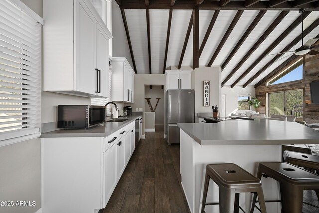 9661 W Coyote Dr, Strawberry, AZ 85544 - kitchen featuring white cabinetry, stainless steel appliances, dark wood-type flooring, a breakfast bar, and vaulted ceiling with beams