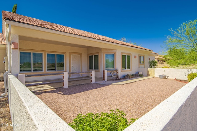 back of property featuring stucco siding, a tile roof, and a patio