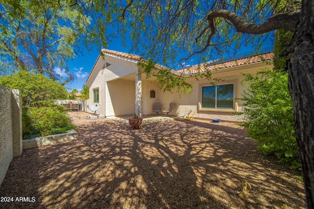 rear view of house with a tile roof, fence, a patio, and stucco siding