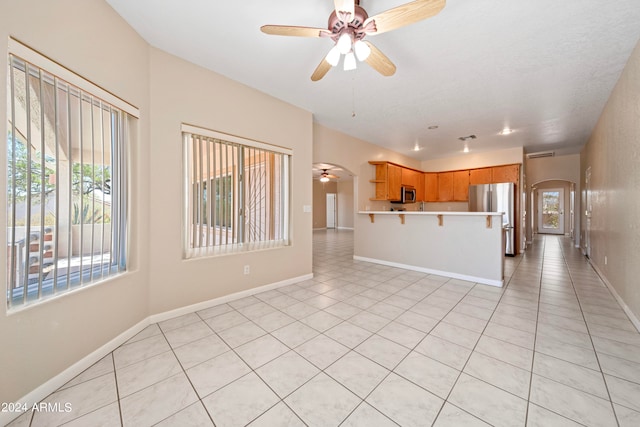 kitchen featuring ceiling fan, light tile patterned floors, stainless steel appliances, and a breakfast bar area