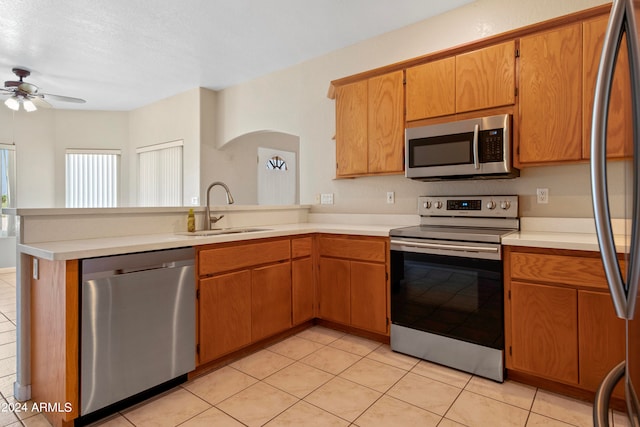 kitchen featuring light tile patterned floors, kitchen peninsula, sink, ceiling fan, and appliances with stainless steel finishes