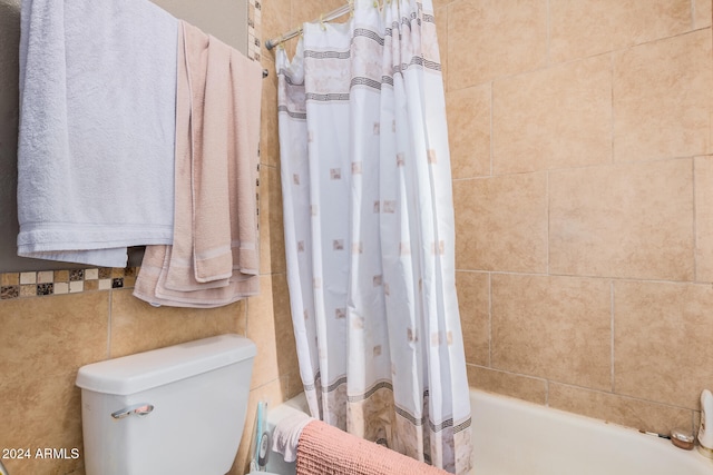 bathroom featuring toilet, tile walls, and shower / tub combo