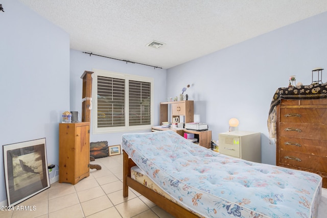 bedroom with a textured ceiling and light tile patterned floors