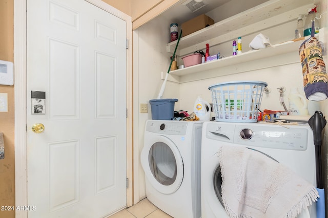 laundry area with light tile patterned floors and washer and clothes dryer