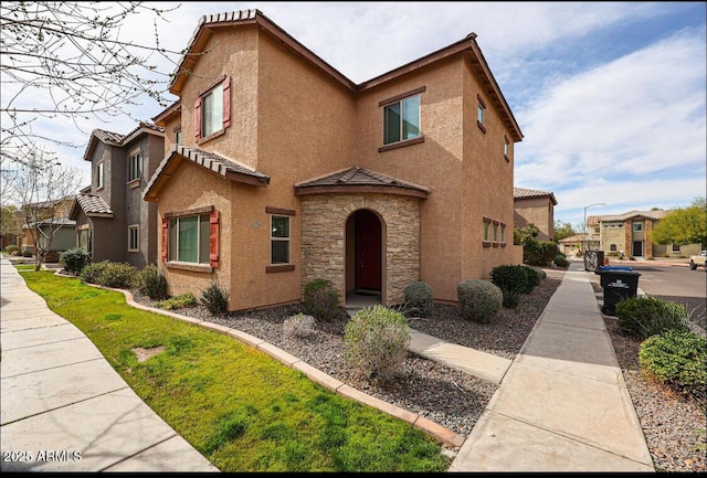 view of front facade with a residential view, stone siding, a tile roof, and stucco siding