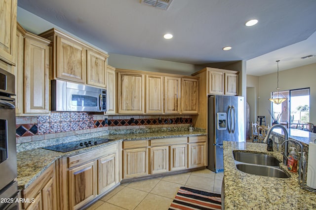 kitchen with appliances with stainless steel finishes, pendant lighting, sink, light tile patterned floors, and light stone countertops