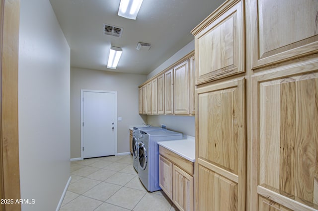 laundry room featuring washer and clothes dryer, cabinets, and light tile patterned flooring