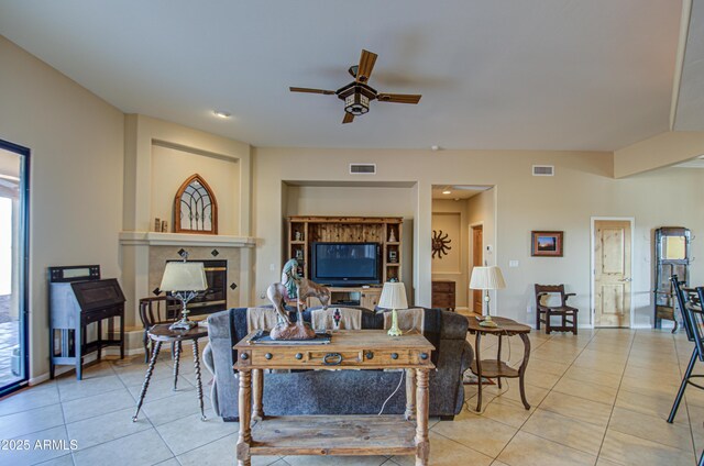 living room featuring a tile fireplace, ceiling fan, and light tile patterned flooring