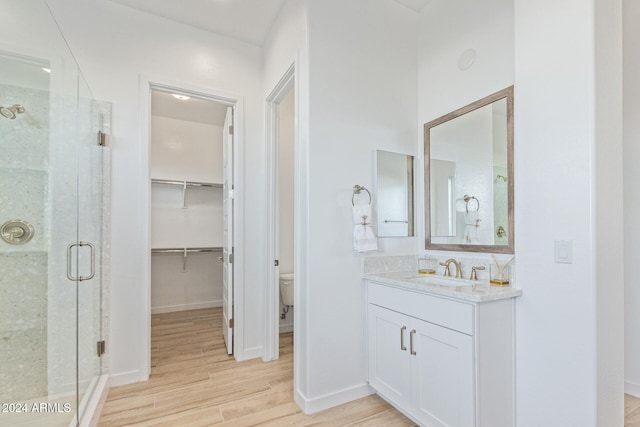 bathroom featuring vanity, hardwood / wood-style flooring, toilet, and a shower with shower door