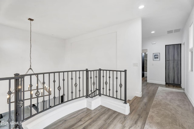 hall with recessed lighting, visible vents, an upstairs landing, wood finished floors, and baseboards