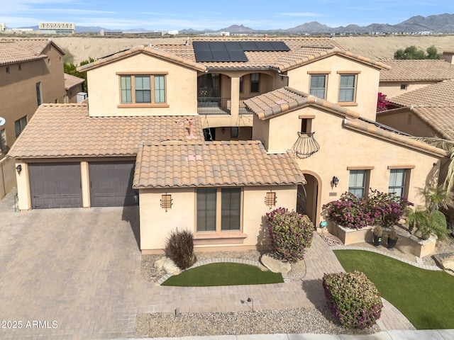 mediterranean / spanish-style home featuring a garage, a tiled roof, decorative driveway, a mountain view, and stucco siding