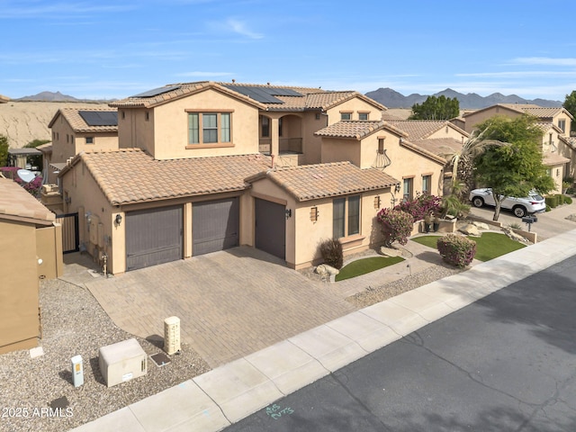 mediterranean / spanish home featuring a mountain view, solar panels, decorative driveway, and a residential view