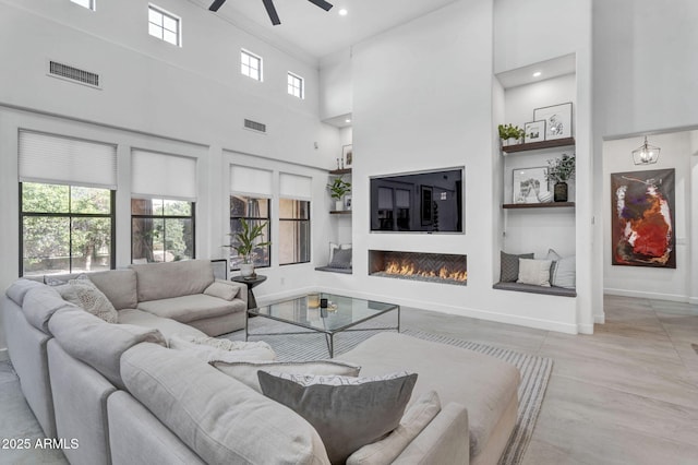 living room with a lit fireplace, a wealth of natural light, and built in features