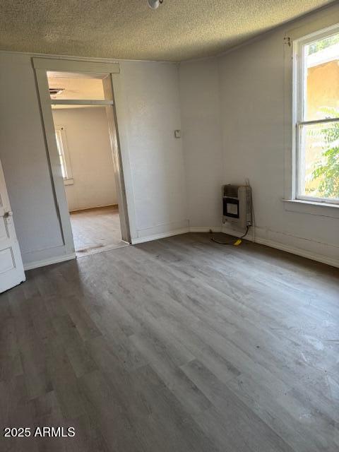 1220 N F Ave, Douglas, AZ 85607 - unfurnished room with heating unit, wood finished floors, plenty of natural light, and a textured ceiling